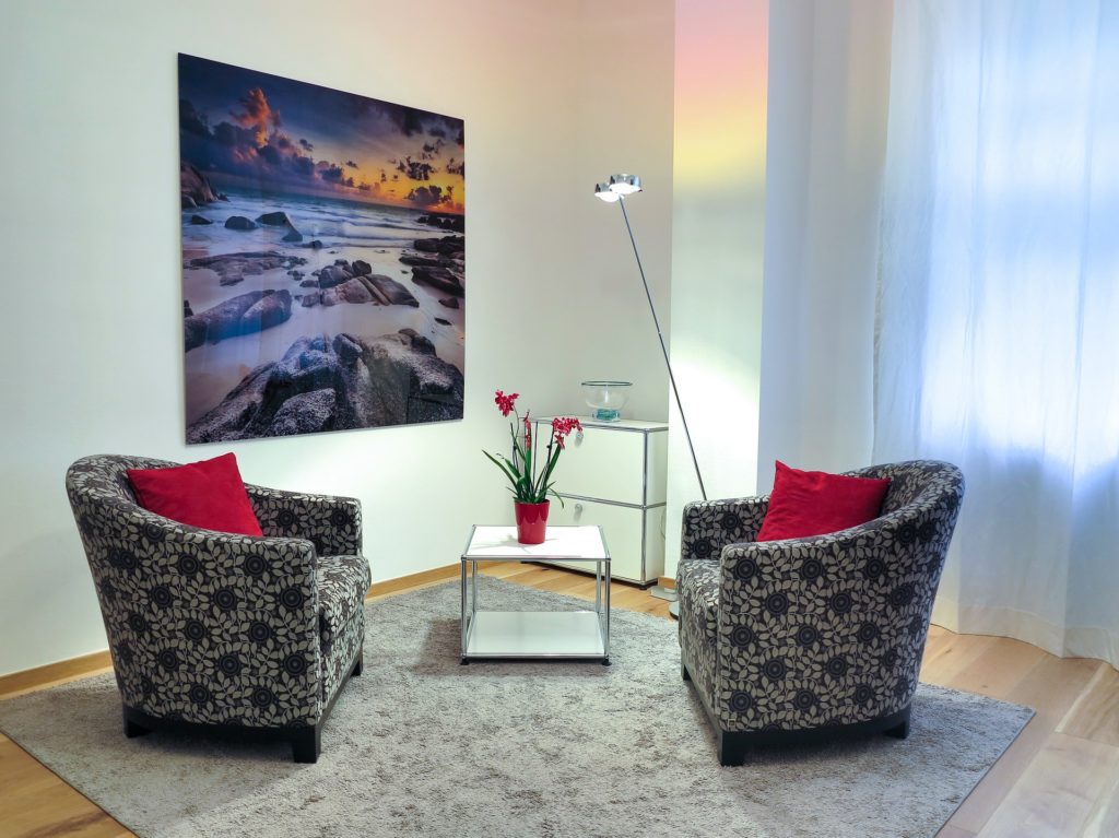 Zwei gemusterte Sessel in Gesprächsformation mit einem Landschaftsbild im Hintergrund