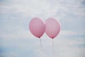 Zwei rosa Luftballons, vor blauem Himmel